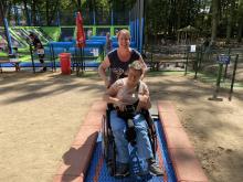 Afbeelding vrouw en jongen in rolstoel in de speeltuin